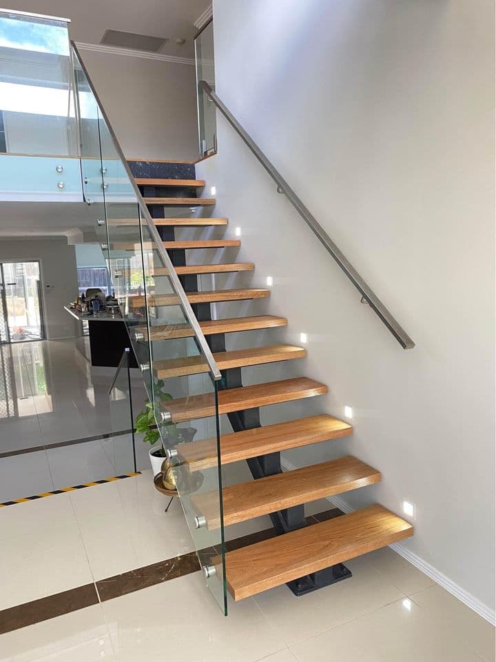 Finished timber staircase with glass balustrades and a steel handrail